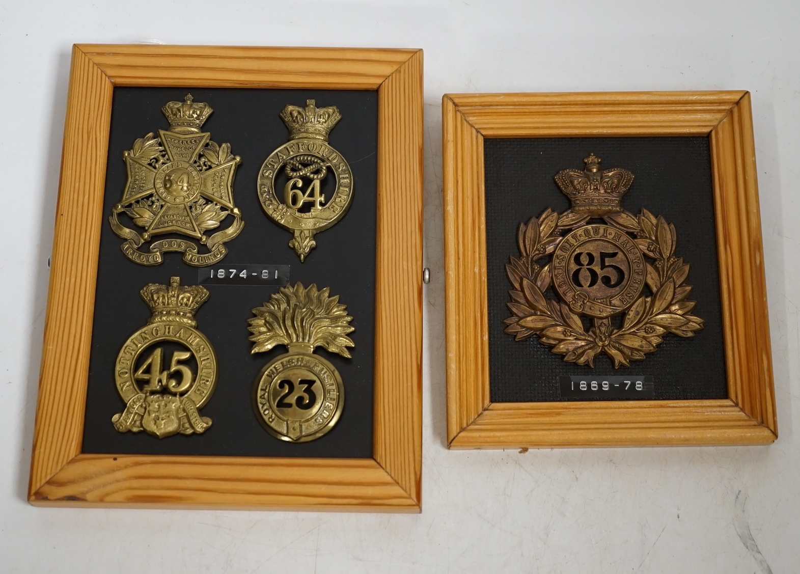 Five military helmet and shako plates mounted on two boards, including; the Nottinghamshire Regiment, the 2nd Staffordshire Regiment, the Royal Welsh Fusiliers, the Cumberland Regiment and the 85th King’s Light Infantry.